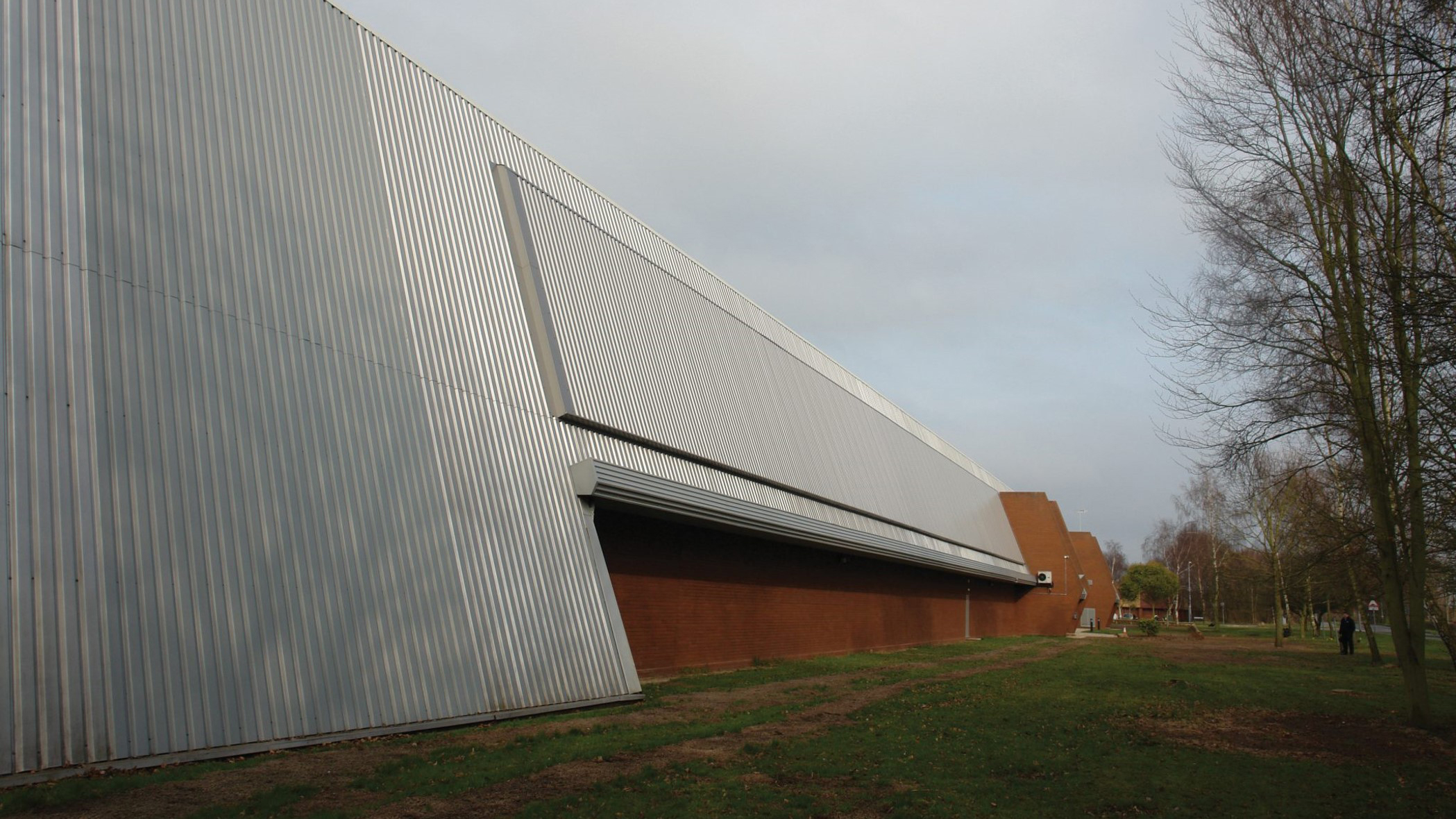SolarWall industrial solar air heating installation on a factory façade with landscaping